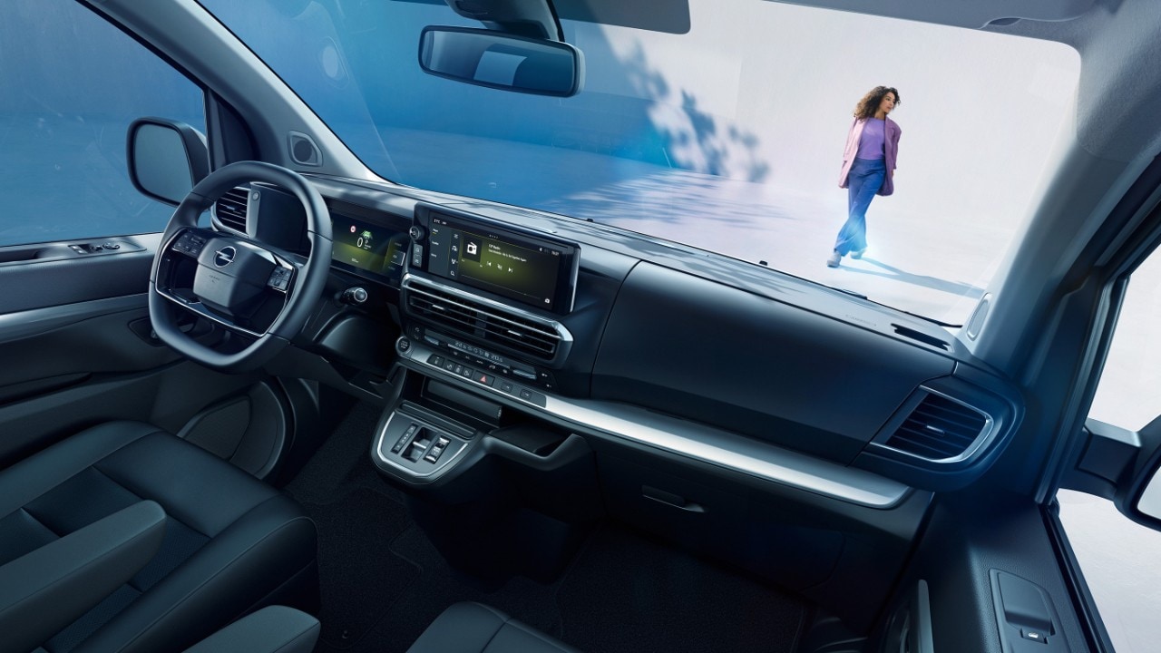 Vue intérieure d'un Opel Zafira blanc depuis le siège passager avec une femme debout à l'extérieur
